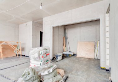 Beyaz beton duvarlı iç inşaat alanı, inşaat malzemeleri ve inşaat iskelesi onarım altında. Sürdürülebilir yaşam tarzı kavramı.