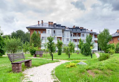 Boş kahverengi ahşap bank yeşil çimen ve ağaçların dinlenme alanı. Kentteki bankların olduğu bahçe manzarası. Arka veya ön bahçe dinlenme alanı kavramı