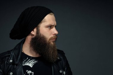 Yanlara bakan deri ceketli ve şapkalı yakışıklı sakallı bir adamın portresi..