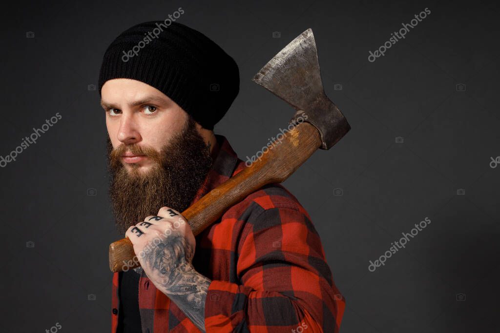 Handsome man with long hair with an ax in his hands on a dark studio background.