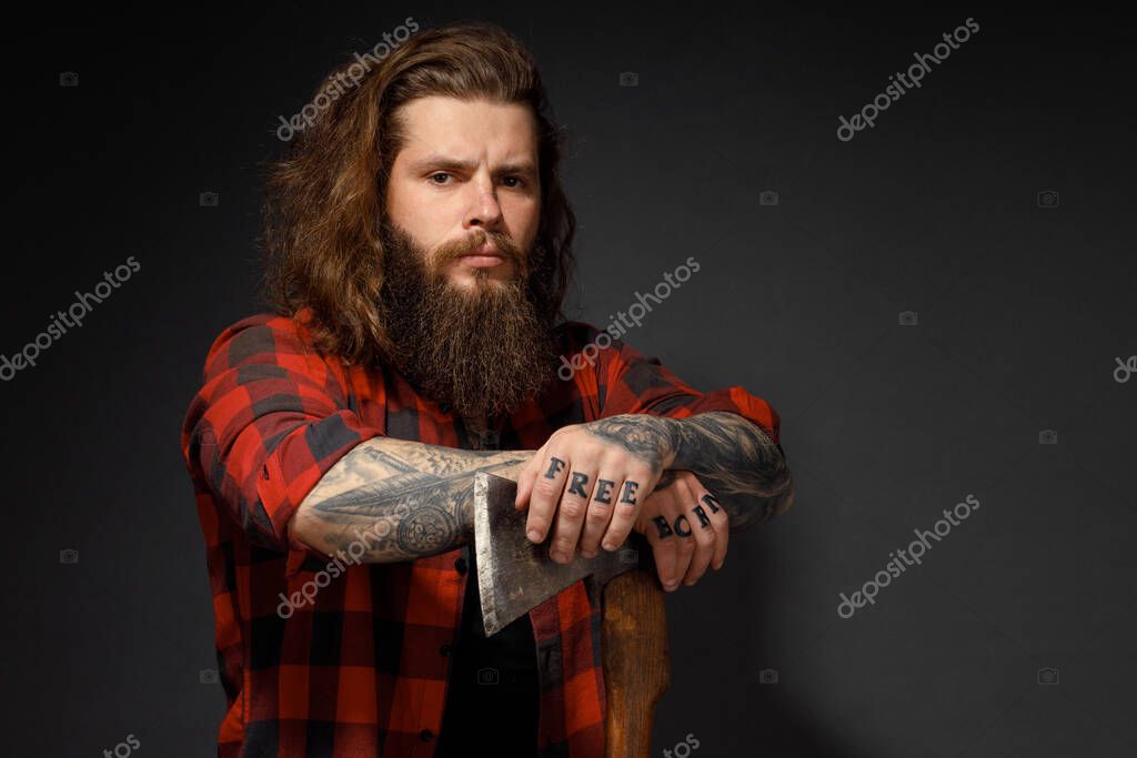 Handsome man with long hair with an ax in his hands on a dark studio background.