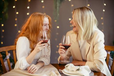 Lezbiyen çift restoranda yemek yiyor kızlar şarap içip sohbet ediyor.