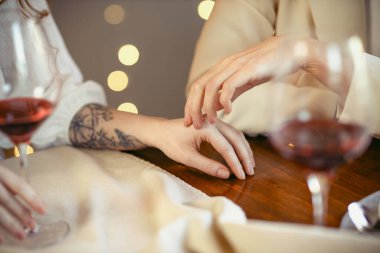 Lezbiyen çift lokantada yemek yiyor. Sevgi dolu bir çiftin ellerinin yakın çekimi.