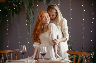 Lezbiyen bir çift restoranda yemek yiyor. Bir kız sevgilisine sarılıyor ve kulağına fısıldıyor.