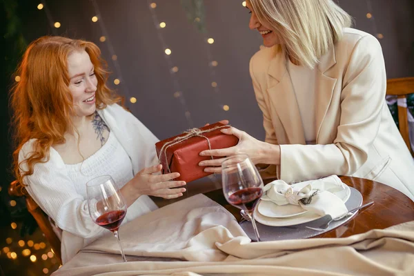 Lezbiyen çift restoranda yemek yiyor. Kız sevgilisine hediye veriyor.