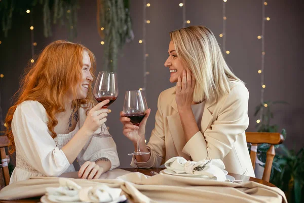 Lezbiyen çift restoranda yemek yiyor kızlar şarap içip sohbet ediyor.