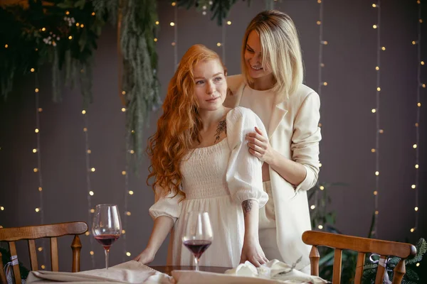 Lezbiyen bir çift restoranda yemek yiyor. Bir kız sevgilisine sarılıyor ve kulağına fısıldıyor.