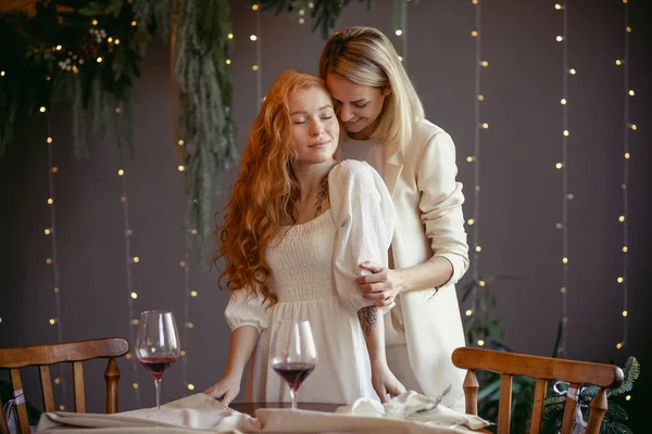 Lezbiyen bir çift restoranda yemek yiyor. Bir kız sevgilisine sarılıyor ve kulağına fısıldıyor.