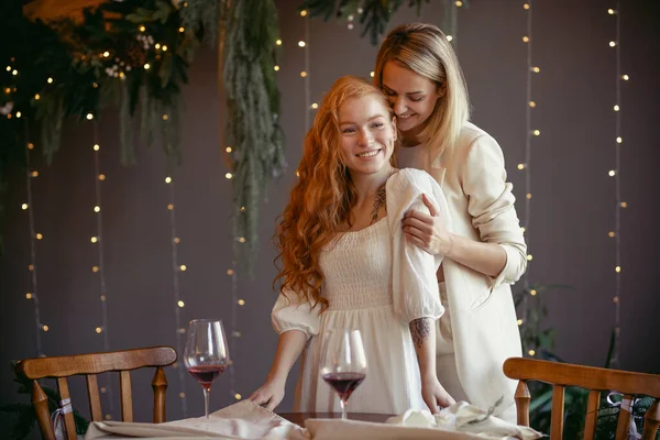 Lezbiyen bir çift restoranda yemek yiyor. Bir kız sevgilisine sarılıyor ve kulağına fısıldıyor.