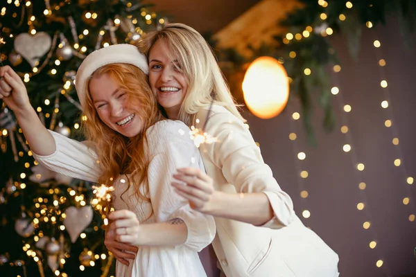 Lesbian Couple Having Dinner Celebrating Holiday Girls Burn Sparklers Smile lizenzfreie Stockfotos