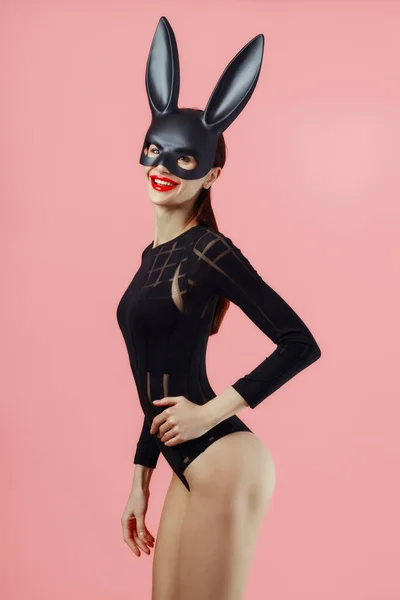 Sexy Frau Trägt Eine Schwarze Maske Osterhase Steht Auf Rosa lizenzfreie Stockfotos