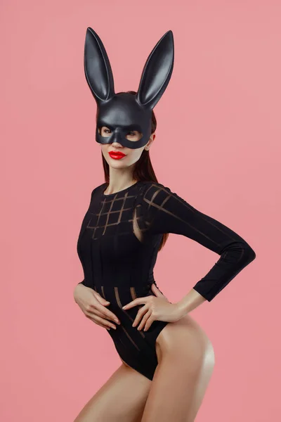 Sexy Frau Trägt Eine Schwarze Maske Osterhase Steht Auf Rosa lizenzfreie Stockbilder