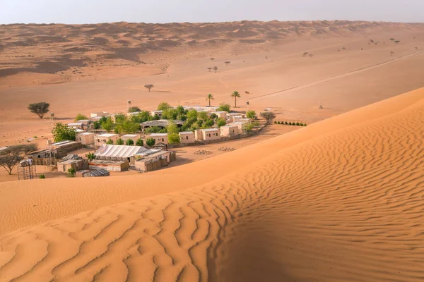 Pequeno acampamento com árvores no meio do deserto árabe. Oásis em Wahiba Sands, Omã. Dia quente nas dunas da península Arábica. — Fotografia de Stock