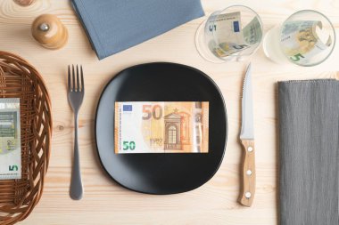 Tabağında yemek yerine euro banknotları olan bir yemek masasının kavramsal çekimi. Artan gıda fiyatları, enflasyon, ekonomik kriz, tüketici fiyatları endeksi kavramı.