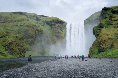 Skogafoss, İzlanda - 06.19.2017: İzlanda 'nın soğuk bulutlu bir yaz gününde Güney İzlanda' daki Skogafoss şelalesinde yürüyen insanlar.