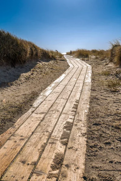 Pasarela de madera en una playa de arena de la isla de Dune, Heligoland, Alemania, en un hermoso día soleado de invierno. Punto infinito en un sendero por el mar del Norte. — Foto de Stock
