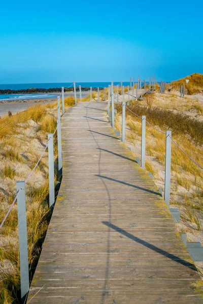 Pasarela de madera en una playa de arena de la isla de Dune, Heligoland, Alemania, en un hermoso día soleado de invierno. Punto infinito en un sendero por el mar del Norte. — Foto de Stock