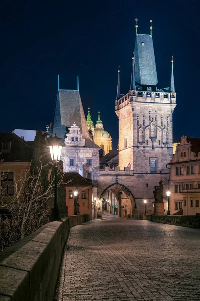 Praga, Chequia - 02.17.2022: Vista de Mala Strana Bridge Towers desde Charles Bridge en la noche oscura. Centro de Praga sin gente. Hermosos edificios históricos en la capital de Europa central. — Foto de Stock