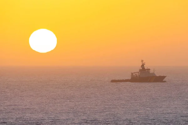 Heligoland, Alemania - 02.26.2022: Pequeño barco nórdico navegando en el mar del Norte con un sol naciente en el horizonte. — Foto de Stock