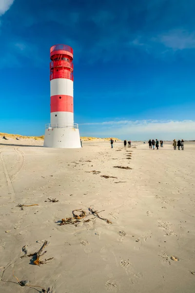Dune and Heligoland, Alemania - 02.27.2022: Foto vertical de personas caminando alrededor del faro en la playa de la isla de Dune, Heligoland, en un hermoso día de invierno soleado con cielo azul. — Foto de Stock