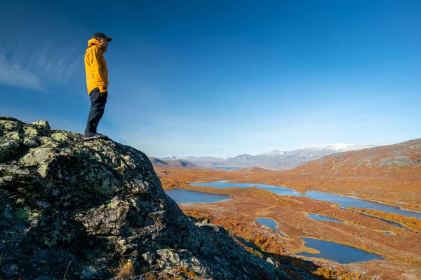 İsveç 'in sonbahar günü, Stora Sjofallet Ulusal Parkı' nın uçsuz bucaksız arktik manzarasına bakan erkek yürüyüşçü. Laponya 'nın dağları ve vadileri. Ahkka massif. Lulep Gierkav 'ın tepesinden görüntüle.