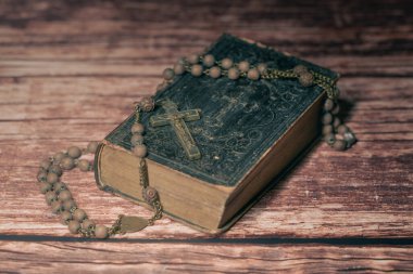 Kapağında bir sürü süs, sarı sayfalar ve eski ahşap masa Hristiyanlığı kavramının eski tespihi olan çok eski ve klasik kutsal İncil 'in geniş bir stüdyo resmi. Namaz vakti..