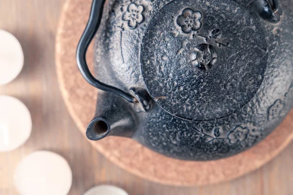 Teiera giapponese in metallo nero su un tavolo di legno con candele da tè e scatola di legno di bastoncini profumati. Natura morta in stile zen in colori caldi e pacifici. Tè caldo per il momento di meditazione. — Foto Stock