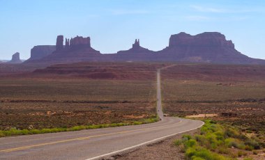 Arizona, Monument Vadisi 'ndeki Rock Door Mesa yakınlarında asfalt yolun alçak açılı çekimi. Amerika 'nın güneybatısındaki Navajo ulus bölgesi. Arizona çölünde ünlü kaya oluşumları. Kırmızı kumtaşı mesa