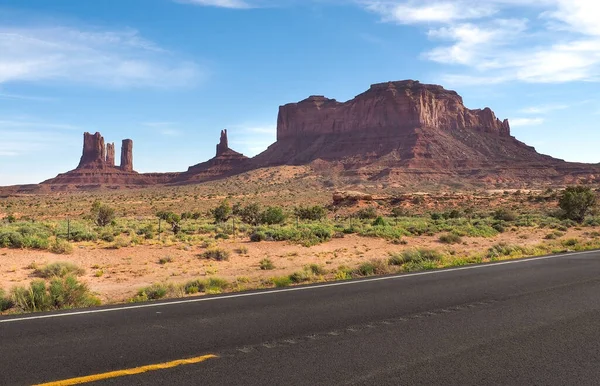 Low angle shot of asphalt road near Rock Door Mesa in Monument Valley, Arizona, USA. Navajo nation area in American southwest. Famoust rock formations in Arizona desert. Red sandstone mesa