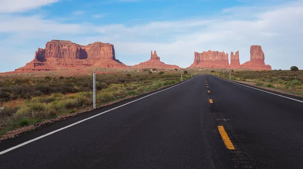 Low angle shot of asphalt road near Rock Door Mesa in Monument Valley, Arizona, USA. Navajo nation area in American southwest. Famoust rock formations in Arizona desert. Red sandstone mesa