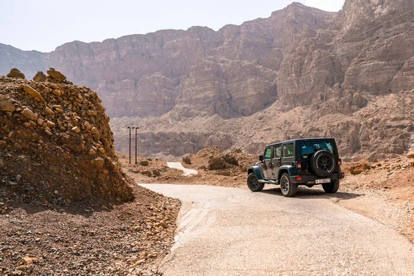 Wadi Tiwi, Umman - 04.05.2018: Umman, Wadi Tiwi 'de sıcak kuru bir vadide dar bir asfalt yolun kenarında siyah Jeep Wrangler. Arabistan 'da seyahat. Sıcak sisli, çok sıcak güneşli bir gün.