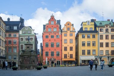 Stockholm, İsveç - 04.16.2017: Stortorget, Büyük Meydan 'ın renkli evlerinin önünden geçen insanlar, Stockholm' ün merkezindeki eski kasaba olan Gamla Stan 'de halk meydanı.
