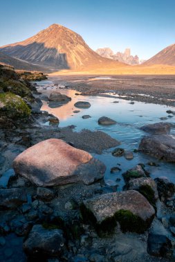 Baykuş nehri yatağı Mt. Asgard, Akshayuk Geçidi, Nunavut. Güneşli sabahın erken saatlerinde güzel kutup manzarası. Uzak ufuktaki ikonik dağlar. Vahşi kuzey.