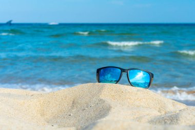 Güneş gözlükleri kumsalda, arka planda mavi deniz dalgalarıyla yatıyordu. Boş zaman, tatil, tatil, yaz konsepti. Baltık Denizi, Polonya