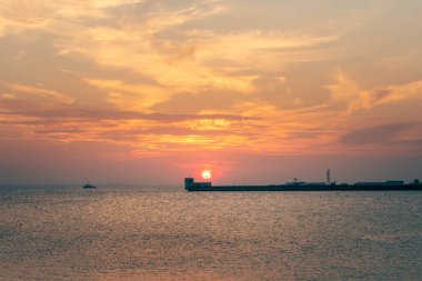 Polonya 'nın Hel limanındaki beton okyanus iskelesinin arkasında dramatik kırmızı gün batımı. Baltık kıyısında yaz akşamı.