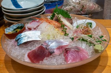 Karışık sashimi parçalı büyük cam buz kasesi. Tokyo 'daki Japon balık restoranında geleneksel saşimi yemeği.