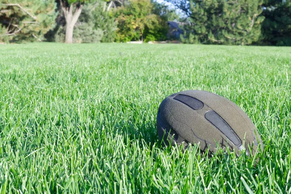 Oude verlaten amerikaanse voetbal bal op het veld alleen liggen in groen gras in het park. Buitensport concept. Horizontale zomer achtergrond foto met kopieerruimte. Actieve levensstijl. Model voor ontwerp — Stockfoto