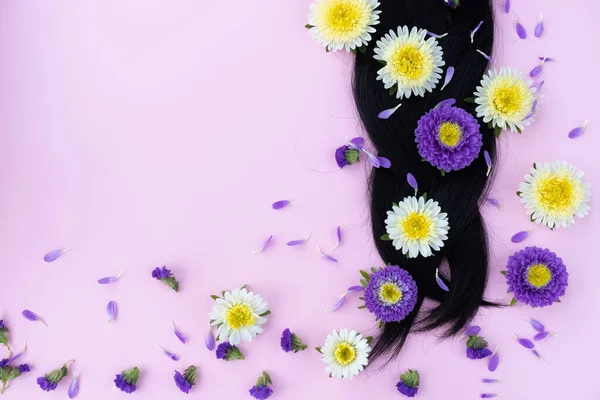 Pigtail de cabelo escuro com flores frescas nele. Conceito de cuidados capilares. — Fotografia de Stock
