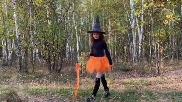 Kleine Hexe mit Zauberstab geht durch einen Wald. Halloween-Konzept. — Stockvideo