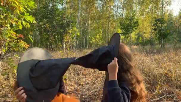 Bonito meninas gêmeas vestidas como bruxas estão lutando e rindo em uma floresta. — Vídeo de Stock