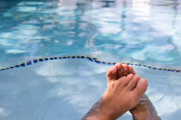 Pies femeninos en el agua en la piscina, primer plano. Mujer relajándose cerca de la piscina. Vacaciones, belleza, concepto de cuidado de los pies. —  Fotos de Stock
