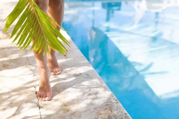 Pies femeninos con palmera caminata cerca de piscina. Enfoque selectivo. —  Fotos de Stock