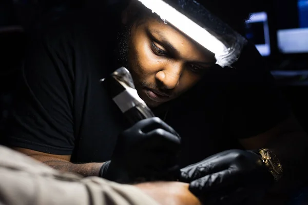 O artista de tatuagem está concentrado em seu trabalho no estúdio de tatuagem. Fechar. — Fotografia de Stock