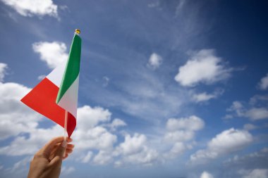 Rüzgarda sallanan İtalyan bayrağı mavi gökyüzü arka planında bir kadının elinde.