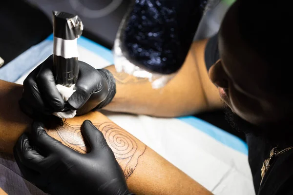 Hands of tattoo artist in black gloves busy with work at tattoo shop. View from above. — Fotografia de Stock