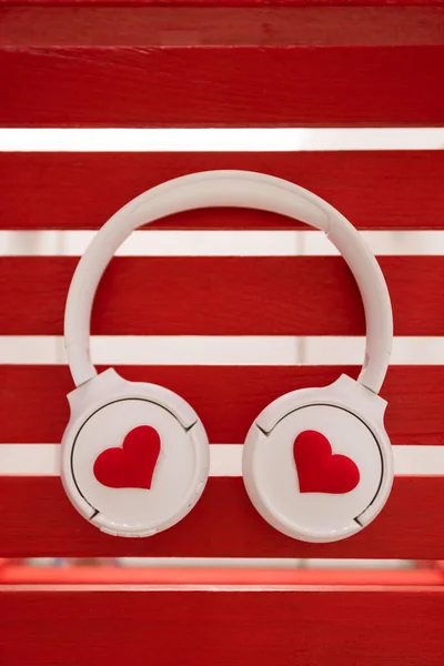 Ακουστικά με καρδιές βρίσκονται σε κόκκινο ξύλινο φόντο. Κλείσιμο. — Φωτογραφία Αρχείου