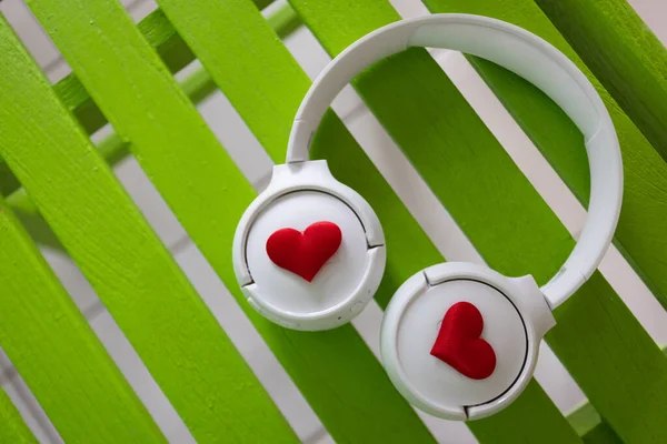 Навушники з сердечками на зеленому дерев'яному фоні. крупним планом . — стокове фото