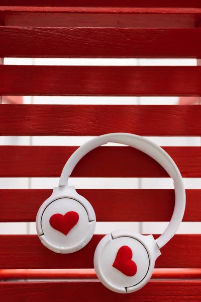 Ακουστικά με καρδιές βρίσκονται σε κόκκινο ξύλινο φόντο. — Φωτογραφία Αρχείου