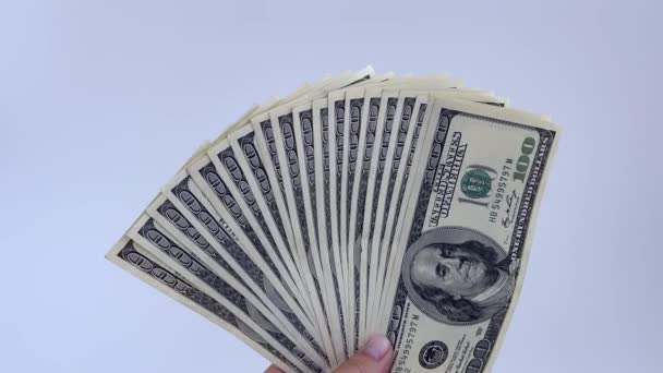Ventilador de 4k de billetes de 100 dólares ondeando en una mano sobre un fondo blanco. — Vídeos de Stock