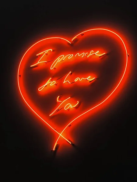Червоне неонове серце з обіцянкою закохатися на чорній стіні . — стокове фото